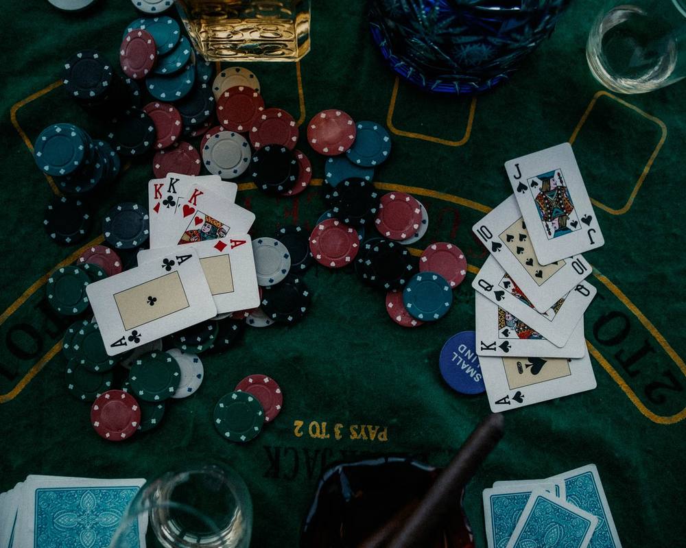 Kartu remi dan tumpukan chip poker di atas meja hijau