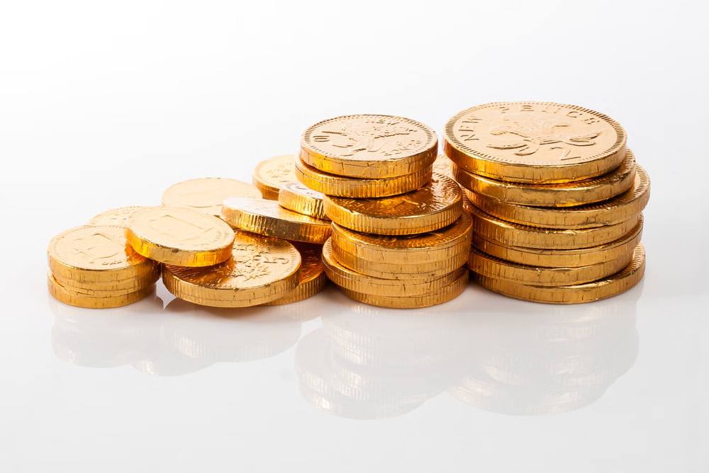 Koin emas bertumpuk di atas meja dengan cahaya hangat